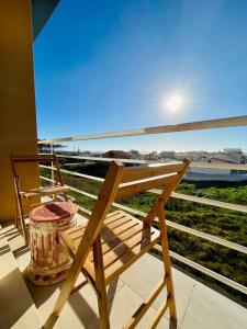 a wooden chair sitting on a balcony with a view of a train at Onda Beach House in Cortegaça