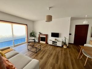 a living room with a couch and a tv at Onda Beach House in Cortegaça