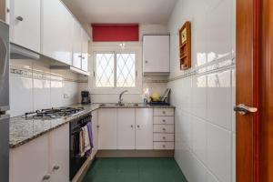 a kitchen with white cabinets and a green floor at Durero in Pineda de Mar