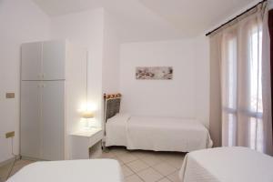 a white room with two beds and a window at mirtagru casa della Sughereta in Budoni