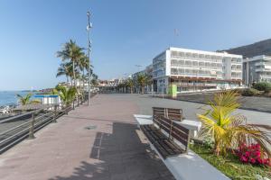 a street with benches and palm trees and a building at Apartamentos Martin - 22 in Puerto Naos
