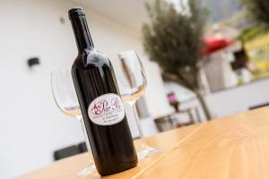 a bottle of wine sitting on a table with two glasses at Peter Paul Studio Penegal in Appiano sulla Strada del Vino