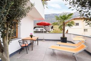 a balcony with tables and chairs and a red umbrella at Peter Paul Studio Penegal in Appiano sulla Strada del Vino
