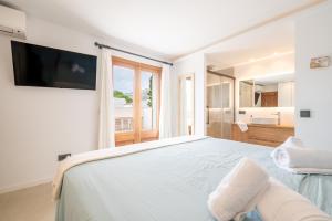 a white bedroom with a large bed and a television at Villa Ana Puerto Pollensa in El Port +23 photos