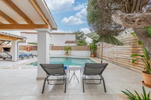 a patio with two chairs and a table next to a swimming pool at Villa Ana Puerto Pollensa in El Port