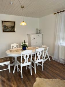 a dining room with a white table and chairs at Ferienwohnung Modelshauser Mühle in Hinterbuch