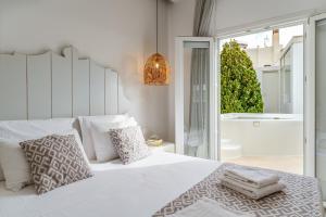 a bedroom with a white bed with pillows and a tub at Aeolos Thalia Suite in Agkidia +17 photos