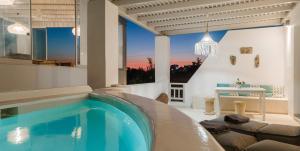 a large swimming pool in a living room with a table at Aeolos Thalia Suite in Agkidia