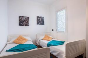 two beds in a white room with pictures on the wall at Spr Ático in Santa Úrsula +12 photos