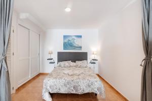 a white bedroom with a bed and two lamps at Vv Timón in Puerto de Mogán