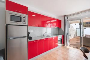a kitchen with red cabinets and a microwave at Vv Timón in Puerto de Mogán