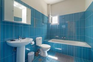 a blue tiled bathroom with a toilet and a sink at Panagis Apartments in Argostoli
