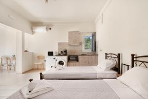 two beds in a white room with a kitchen at Panagis Apartments in Argostoli