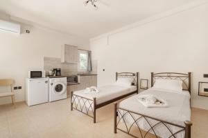two beds in a room with a kitchen at Panagis Apartments in Argostoli
