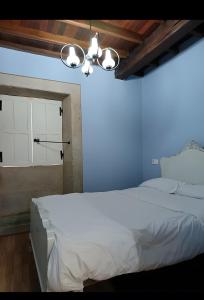 a bedroom with a white bed and a blue wall at O Lar de Natalio in Rianjo