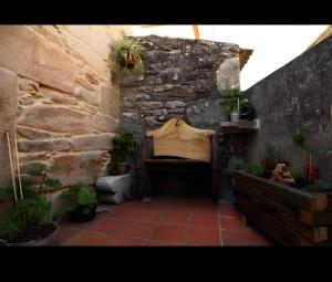 a patio with a stone wall and a bench with potted plants at O Lar de Natalio in Rianjo