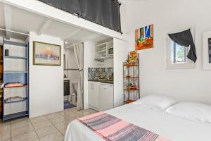 a white bedroom with a bed and a kitchen at Appartement Pinède Romane Fréjus in Fréjus
