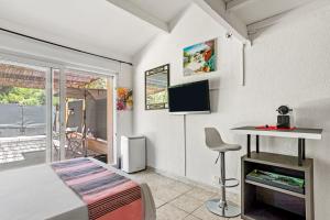 a bedroom with a bed and a desk and a tv at Appartement Pinède Romane Fréjus in Fréjus