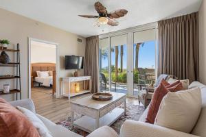 a living room with a couch and a table and a tv at Gulf Front condo with Beach access and shared Pool in Fort Walton Beach