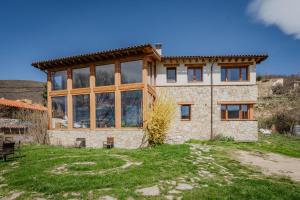 a large stone house with a large window at Ecolgica Casa Del Sol 1 in Navacepeda de Tormes