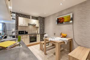 a kitchen with a table and a tv on the wall at Studioapartment am Hafen in Flensburg +17 photos