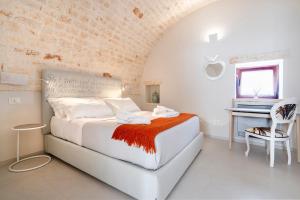 a white bedroom with a bed and a desk at Civico40 Suite in Locorotondo