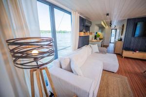 a living room with a white couch and a large window at Wohlfühl-Hausboot Elements Woma D13 in Fürstenberg