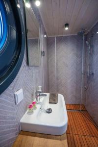 a bathroom with a white sink and a shower at Wohlfühl-Hausboot Elements Woma D13 in Fürstenberg +8 photos