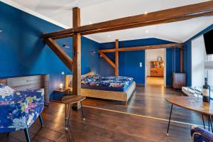 ein Schlafzimmer mit blauen Wänden, einem Bett und einem Tisch in der Unterkunft Waldhusenwarft in Pellworm