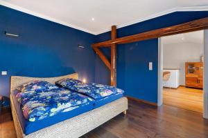 ein blaues Schlafzimmer mit einem Bett und einer blauen Wand in der Unterkunft Waldhusenwarft in Pellworm