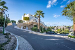 a street with palm trees and a white building at Norah’s House in Carvoeiro