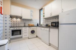 a kitchen with white cabinets and a washer and dryer at Norah’s House in Carvoeiro