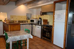 a kitchen with a table and a white refrigerator at Gîte De La Poucinière in Saint-Sauves- dʼAuvergne