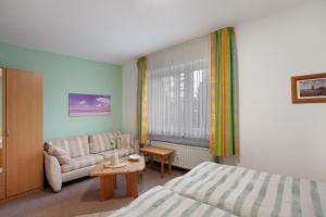 a bedroom with a bed and a couch and a table at Birkenhauer inkl Meine Card plus in Willingen