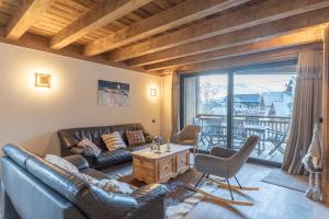 a living room with a leather couch and a large window at Charlotte la Marmotte in Morillon
