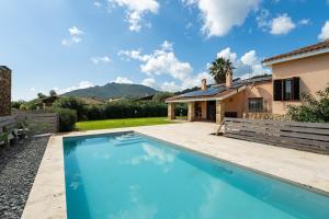 a swimming pool in front of a house at Villa Ulivi 10 in Is Molas 