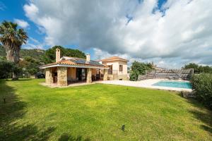 a house with a yard and a swimming pool at Villa Ulivi 10 in Is Molas 
