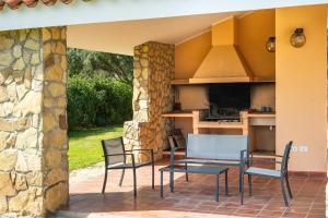 a patio with a table and chairs and a kitchen at Villa Ulivi 10 in Is Molas 