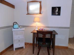 a desk with a lamp and a table with a chair at La Gourmantine in Polignac