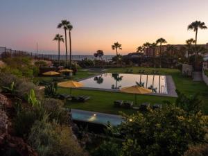 an outdoor pool with umbrellas and palm trees at Fantastic Villa Verano in San Miguel de Abona