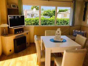 a living room with a television and a table with a tableablish at Chalet Strandliebe Bredene in Bredene