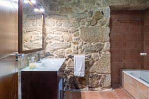 a bathroom with a sink and a stone wall at Lugar Da Xacra in Meder +32 photos