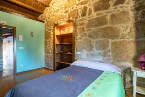 a bedroom with a stone wall and a bed in a room at Lugar Da Xacra in Meder
