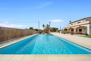 a swimming pool with blue water in front of a fence at Mas del Vedell in L'Ampolla