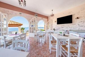 a restaurant with white tables and chairs and a flat screen tv at Stefanos place Studio sea View 7 in Corfu