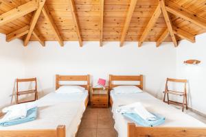 two beds in a room with wooden ceilings at Green Pearl in Lachania +19 photos