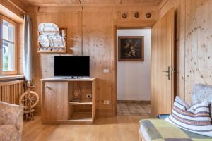 a living room with wooden walls and a television on a table at Haus Thurn Apartment A in Castelrotto