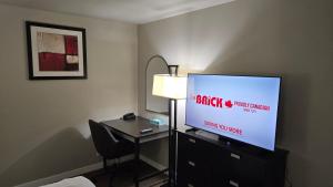 a hotel room with a tv and a desk with a chair at Red Coat Inn Motel in Fort Macleod