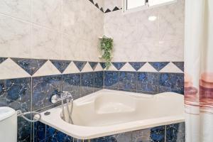 a bathroom with a white tub and blue tiles at Butterfly apartment in Nerja +16 photos