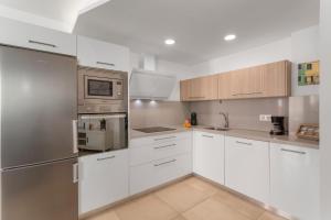 a kitchen with white cabinets and stainless steel appliances at Sunset Star Arguineguin in Arguineguín